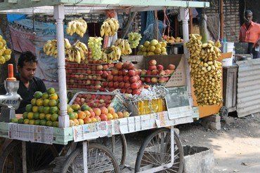 Obstverkäuferwagen beladen mit Bananen, Äpfeln und Orangen.