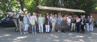 Gruppe von Personen mit einer Pferdekutsche bei einem Ausflug.