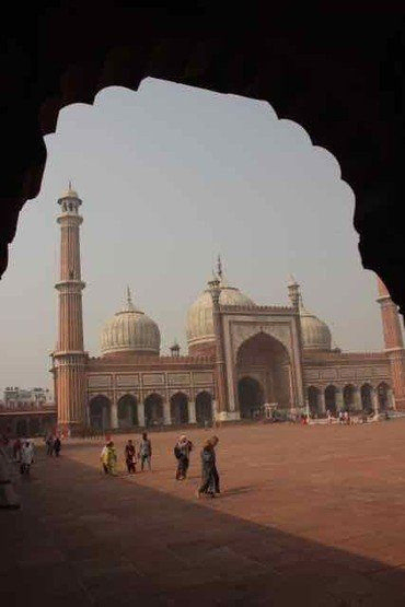 Jama Masjid Moschee mit Minaretten und Kuppeln, von einem Torbogen eingerahmt.