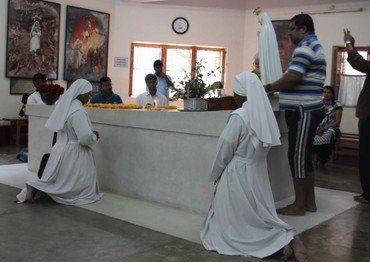 Nonnen knien im Gebet vor einem Altar mit einer Madonnenstatue.