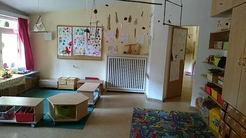 Heller, ordentlicher Kindergartenraum mit Kunstwerken, Möbeln und Spielzeug.