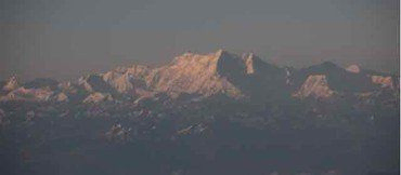 Schneebedeckter Gebirgszug bei Sonnenuntergang, niedrigere Gipfel im Schatten.
