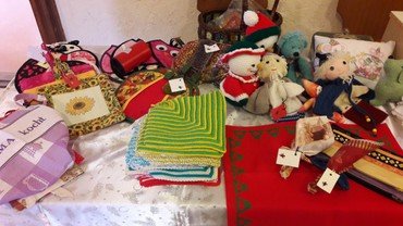 Tischpräsentation verschiedener handgemachter Bastelartikel, einschließlich Strick- und Stoffwaren.