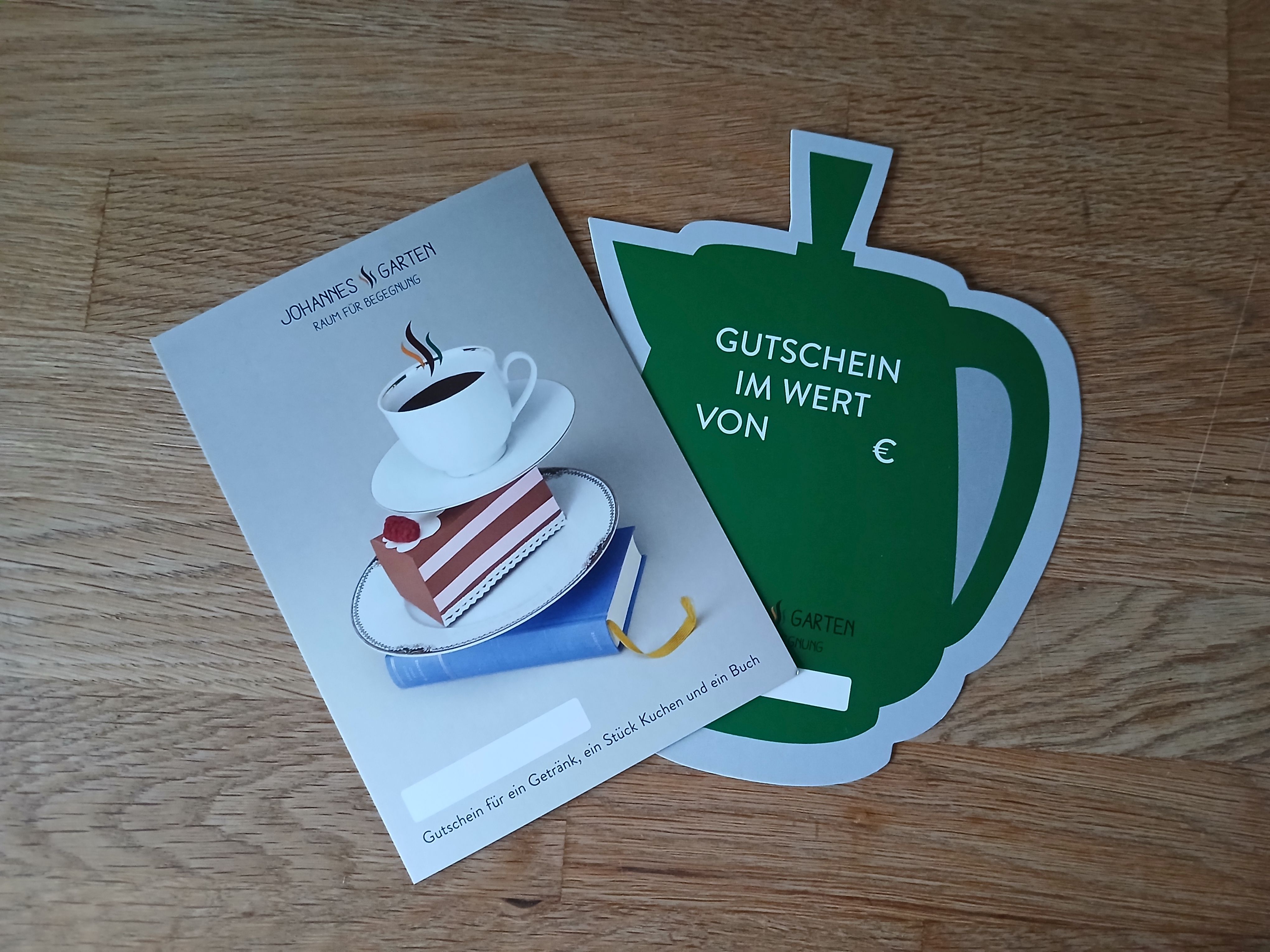 Broschüre „Johannes‘ Garten“ und Teekannen-förmiger Gutschein.