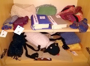 Regale mit Strickwaren, Büchern und einem Stoffschaf.