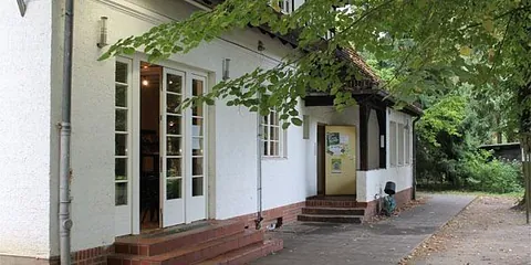 Weißes Gebäude mit großen Glastüren und Seiteneingang.