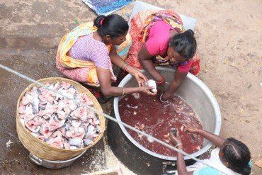 Frauen putzen Fisch in großen Wannen auf einem Markt.
