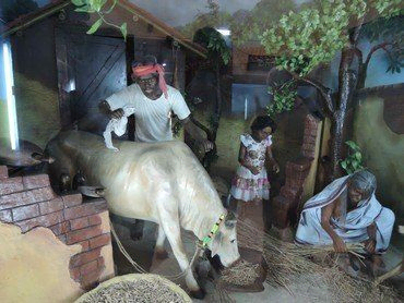 Diorama des Dorflebens mit Figuren, darunter ein Mann mit einer Kuh.
